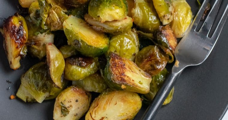 baked brussels sprouts on black plate with fork