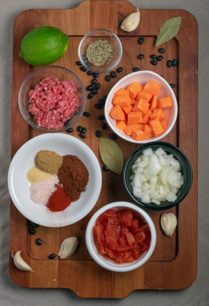 Ingredients for Black Bean Sweet Potato Chili in small bowls on wood tray