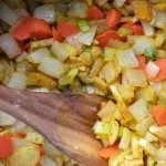 Vegetables in cooking pot with wooden spoon