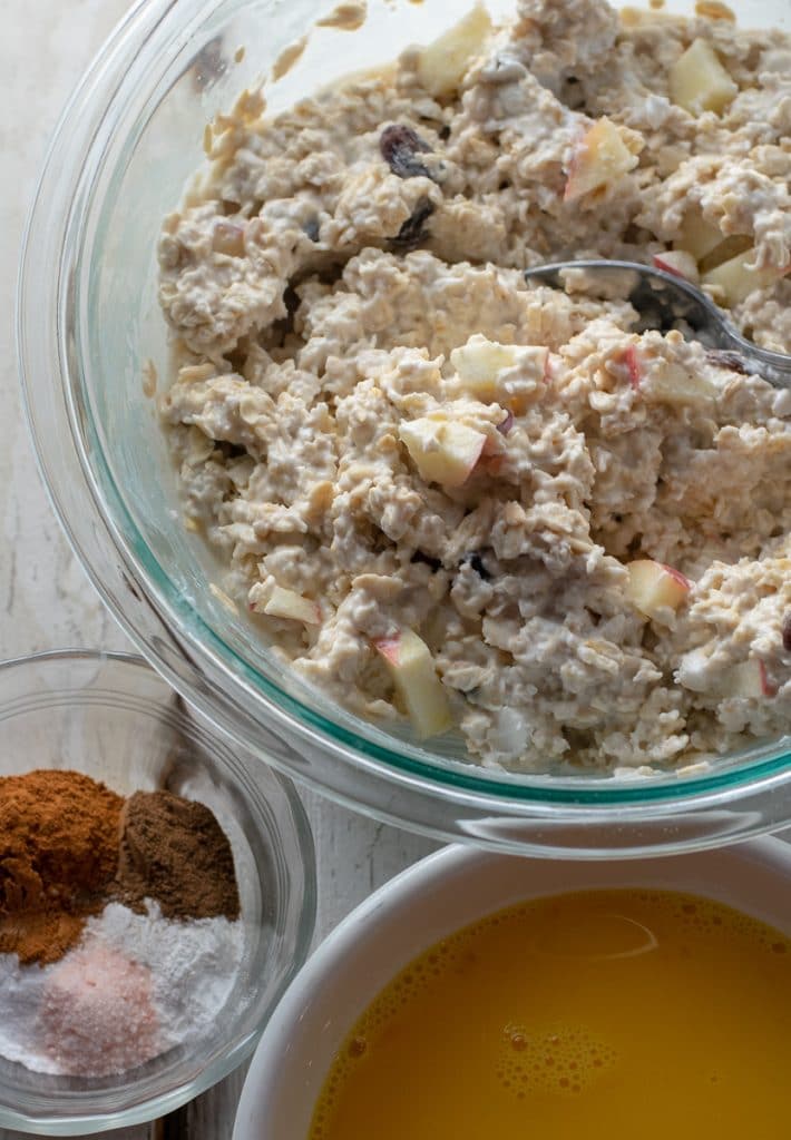 Oats, raisins and apples in coconut milk with eggs and spices in bowls