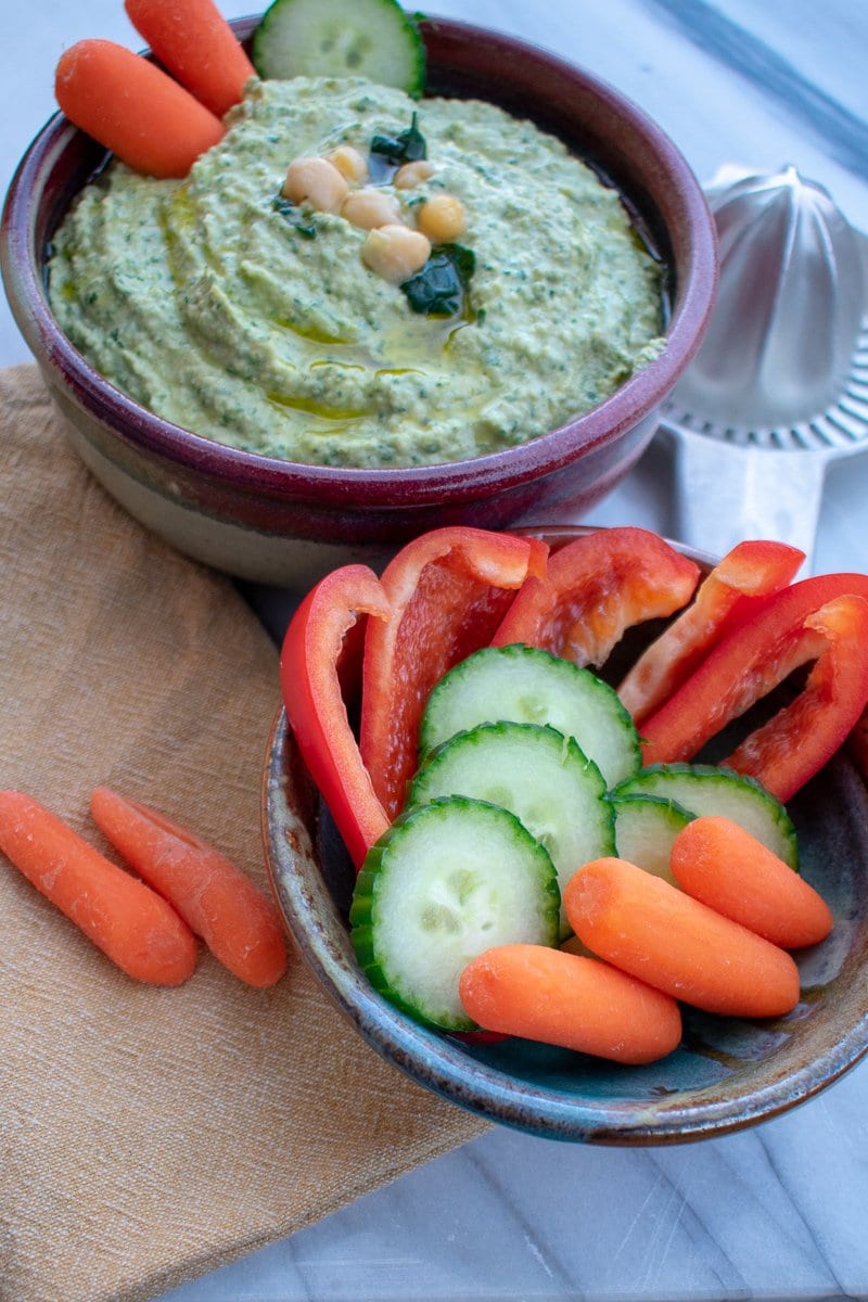 Garlicky spinach artichoke hummus in red bowl from side