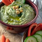 Garlicky spinach artichoke hummus in red bowl overhead view