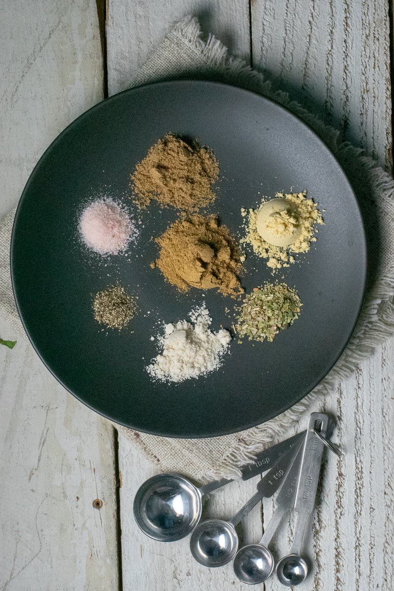 Taco seasoning ingredients on black plate with measuring spoons