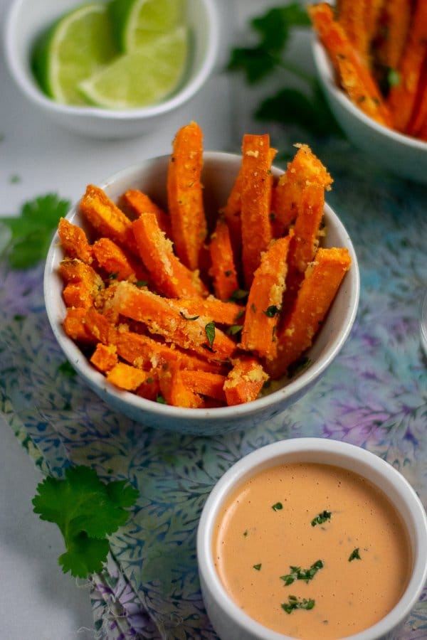 Roasted Sweet potato fries and sriracha mayo in small bowls with limes
