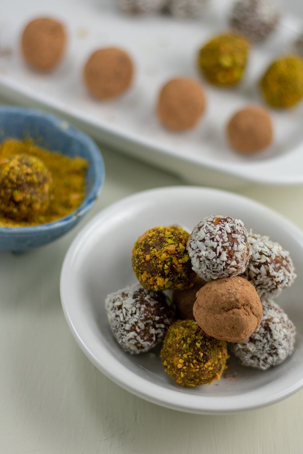 raw date-apricot almond-butter bites in white bowl with coating bowl behind