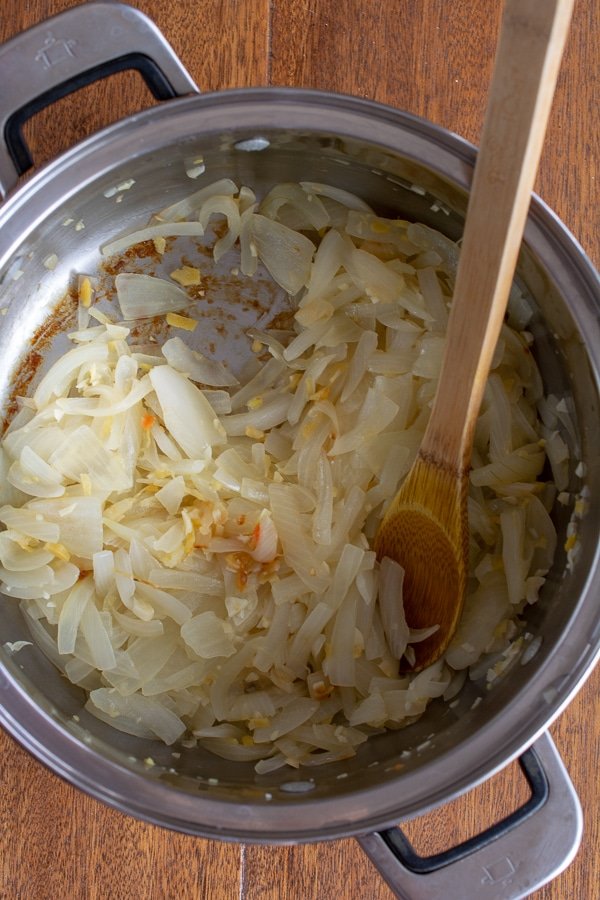 caramelizing onions in stainless steel pot with wooden spoon