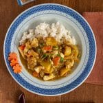Japanese chicken curry on rice on a blue plate with chopsticks and condiment dish