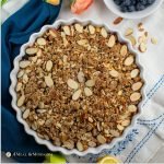 blueberry apple crisp in white tart pan on tablecloth