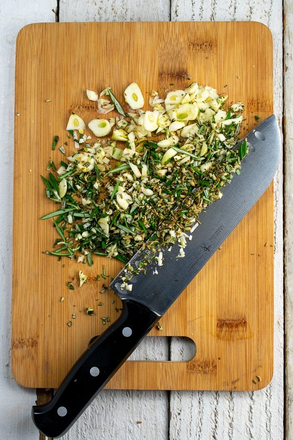 chopping garlic, fennel and rosemary on bamboo board