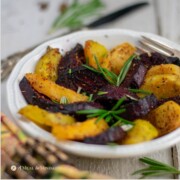 roasted rutabagas and red and gold beets on white dish with gold napkin