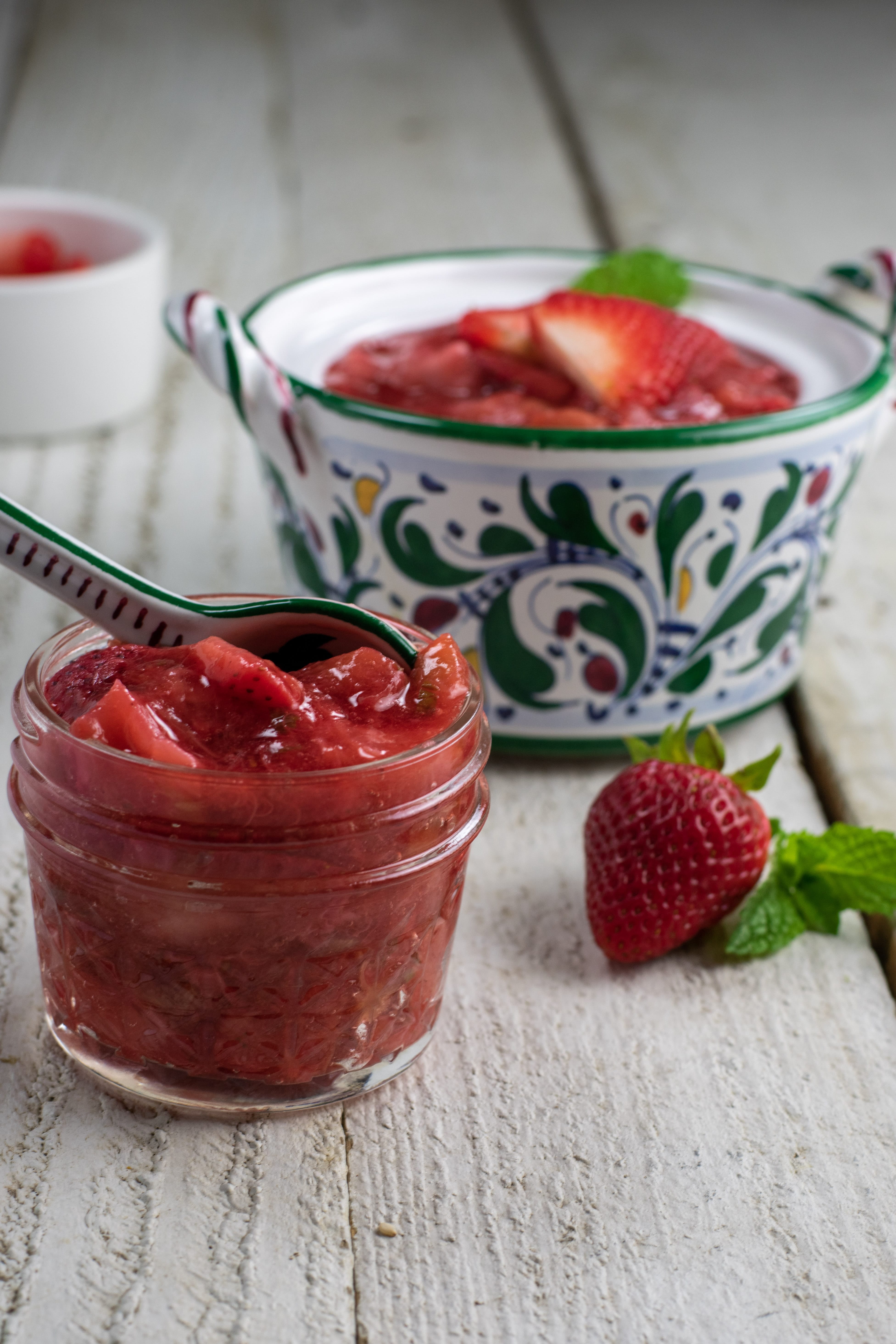 strawberry rhubarb compote in patterned and clear dishes on white table