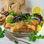 easy almond flour crusted salmon on plate with salad greens and lemon