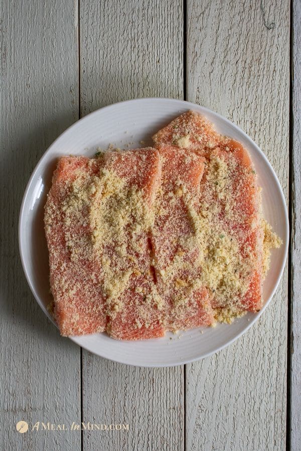 salmon fillets with almond flour coating before cooking on white plate