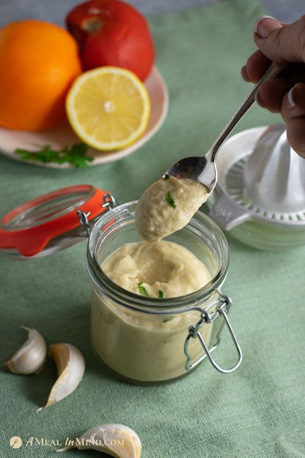 baba ghanoush salad dressing in glass jar with tomatoes in background