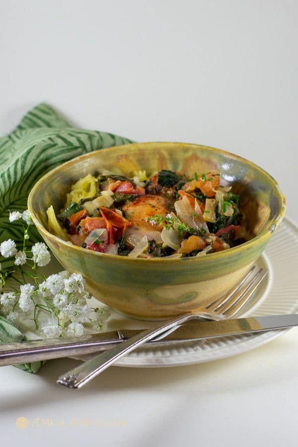 tuscan chicken with spinach, tomatoes, and artichokes with spaghetti squash pasta in ceramic bowl