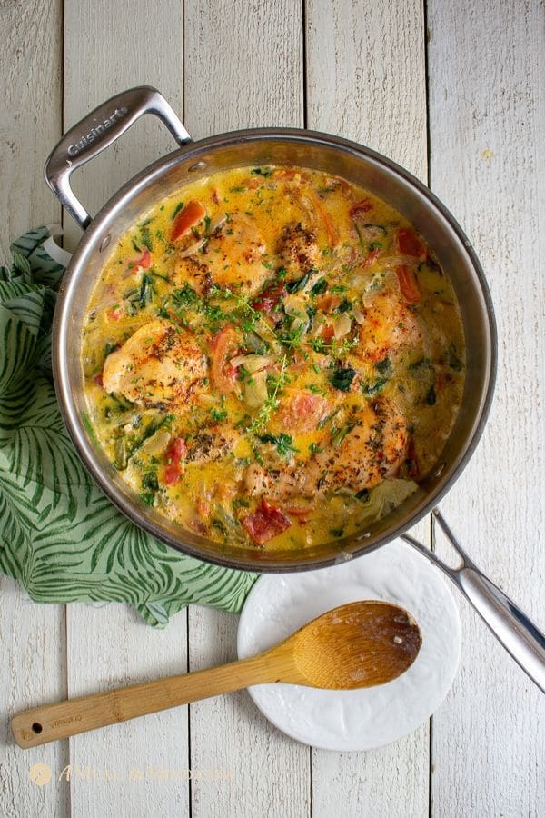 savory tuscan chicken with spinach, tomatoes, and artichokes in steel pan