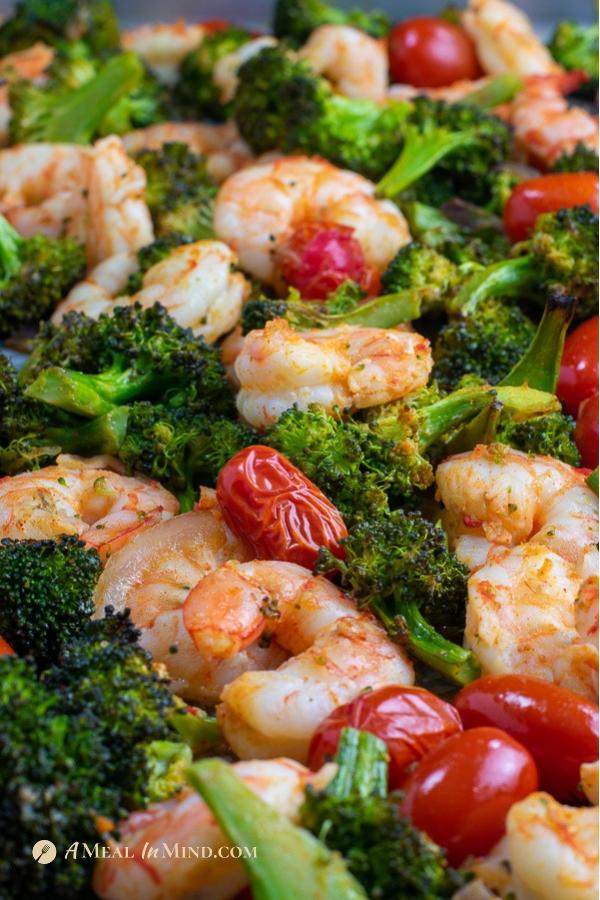 side view of shrimp, broccoli and tomatoes on sheet pan