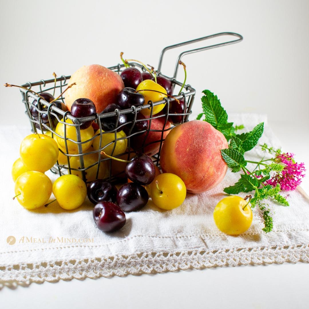 gorgeous organic peaches, plums and cherries in wire basket