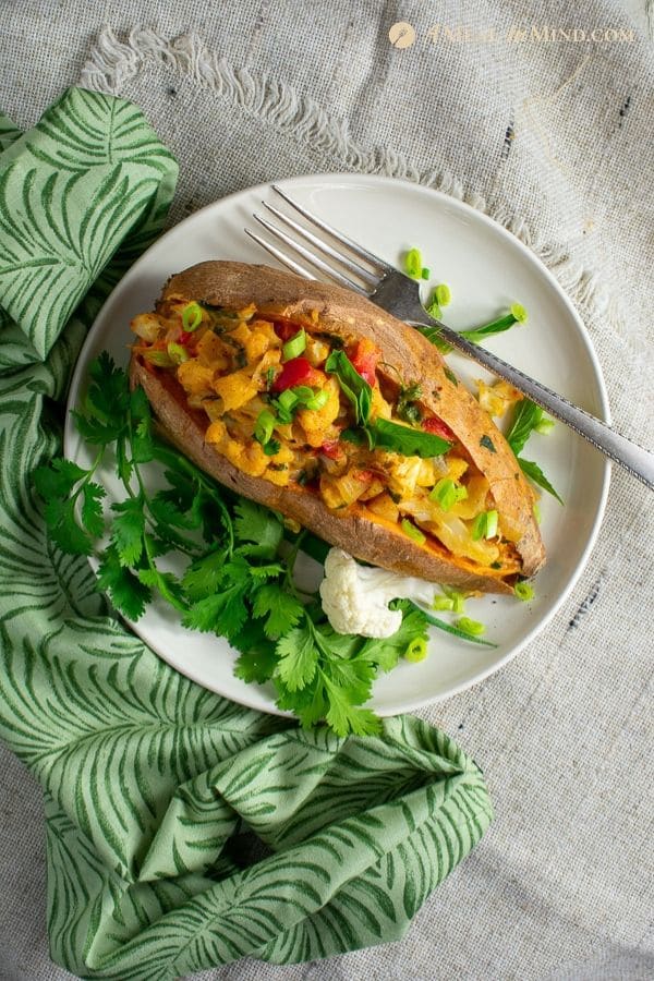 one thai massaman curry stuffed sweet potato on white plate with green cloth