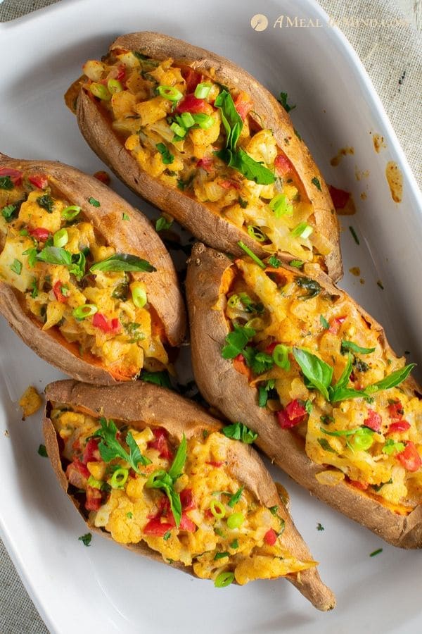 four thai massaman curry stuffed sweet potatoes in white ceramic baking pan