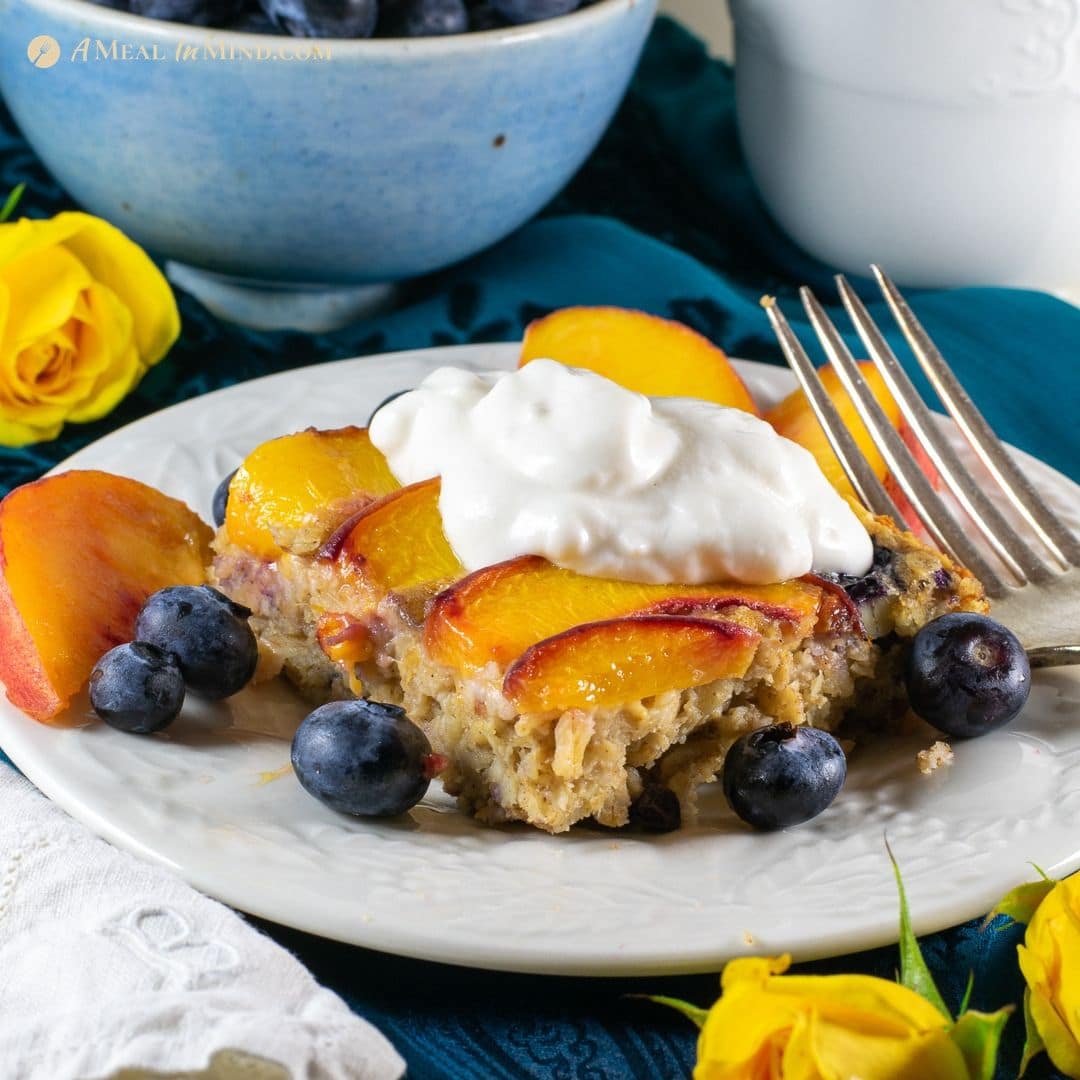 serving of peach oatmeal breakfast clafoutis with almond yogurt on white plate