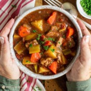 old fashioned oven baked beef stew in bowl held in hands