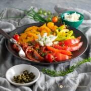 heirloom tomato salad with capers and feta on black plate