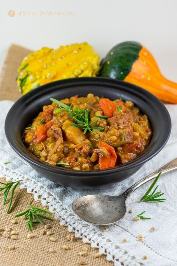 easy beef barley pumpkin stew in black bowl on white cloth