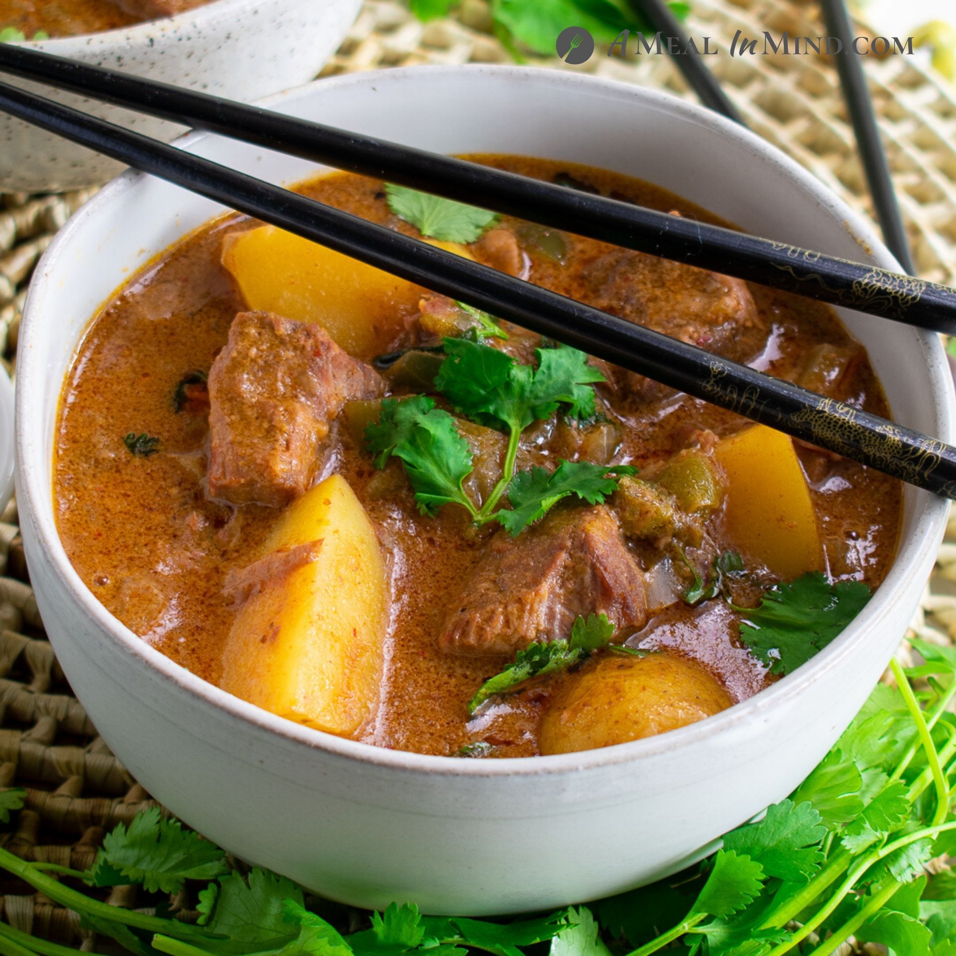 thai massaman beef curry with potatoes in white bowl