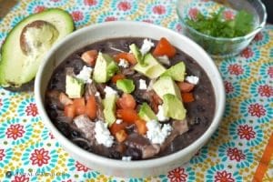 Green chile chicken enchilada soup in white bowl with toppings