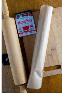 Roll of dough in parchment for cranberry almond-flour pinwheel cookies and MacroLife powder