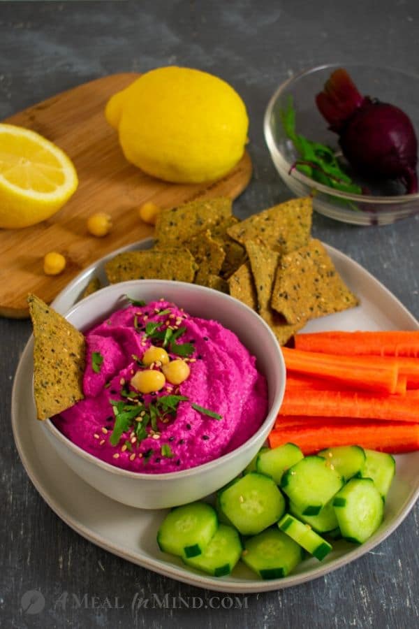 Beet-Artichoke Hummus in small bowl with vegetables and chips