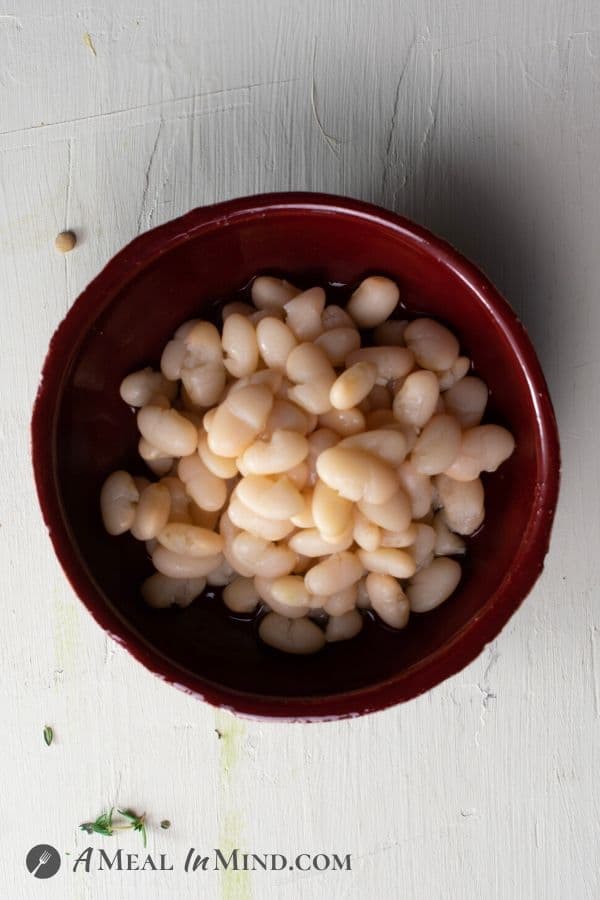cooked white beans in red bowl