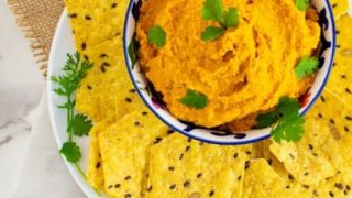 Moroccan Roasted-Carrot Hummus on white plate with multigrain chips