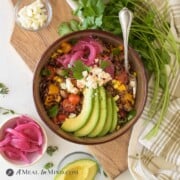 mexican quinoa bowl in brown bowl with toppings