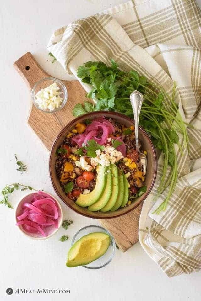 Mexican Quinoa Bowl with Corn and Peppers on wooden board with cloth