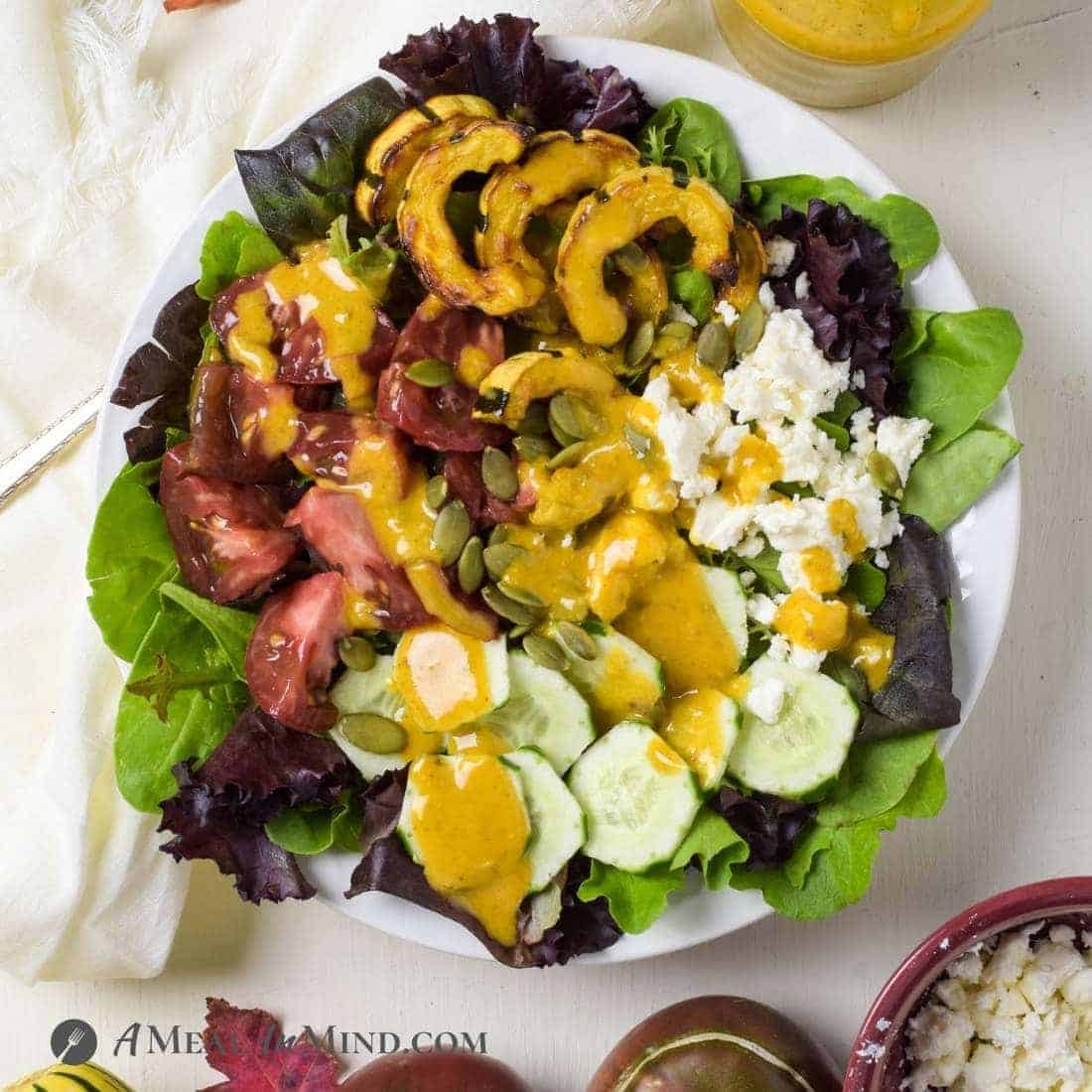 Roasted Delicata and heirloom tomato salad in white bowl with pumpkin dressing