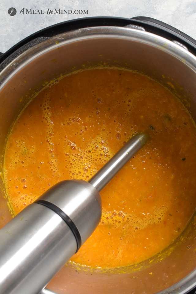 roasted butternut tomato soup being pureed with immersion blender