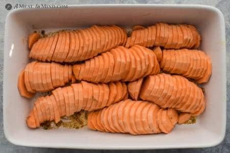 sliced sweet potatoes arranged in white baking dish