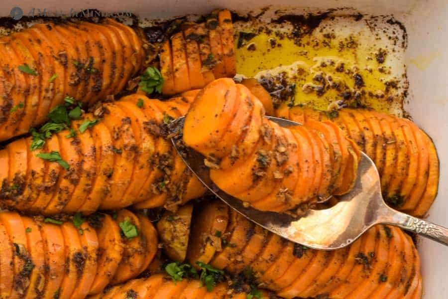 roasted sweet potatoes being served from white baking dish