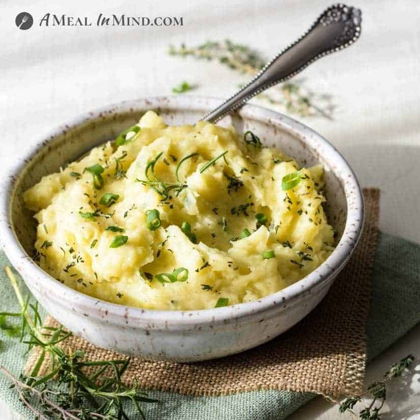 garlic mashed potatoes in speckled bowl with spoon