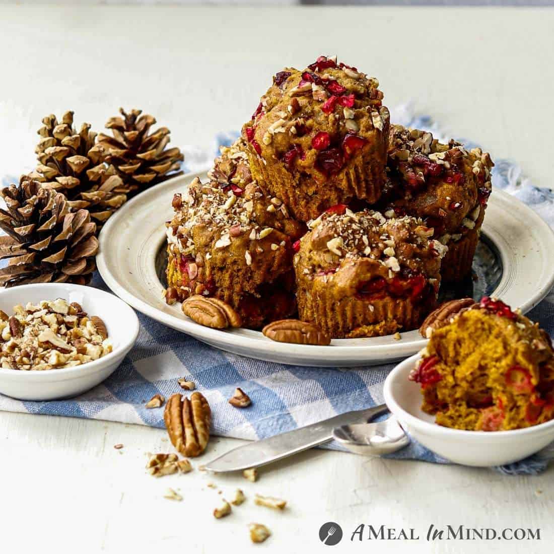 Cranberry-Pecan Pumpkin Muffins on ivory plate with scattered pecans