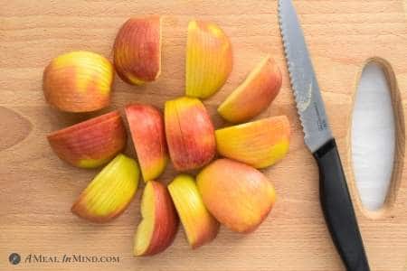 sliced apples on wood board with knife