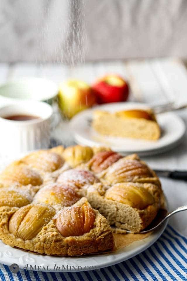 german apple cake from side with powdered sugar being sprinkled on