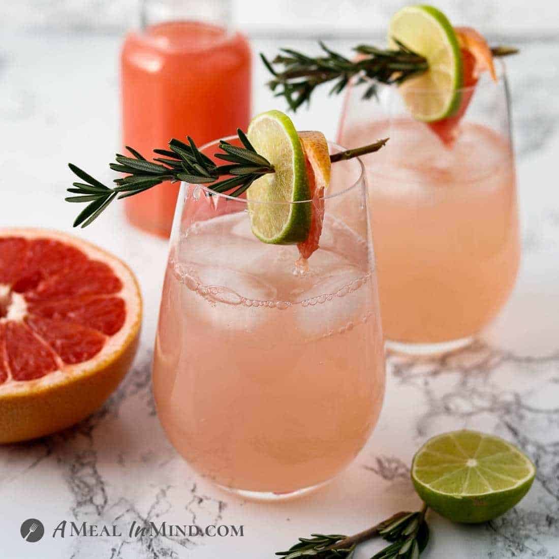 paloma mocktails with organic sugar in two tall glasses with rosemary garnishes