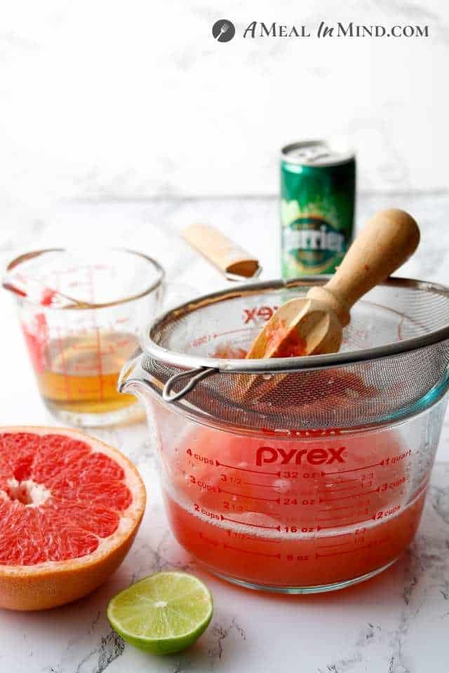 juicing grapefruit into a measuring cup using a reamer and strainer