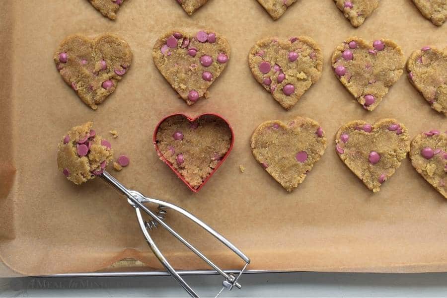 heart cookies in cookie cutter on baking sheet