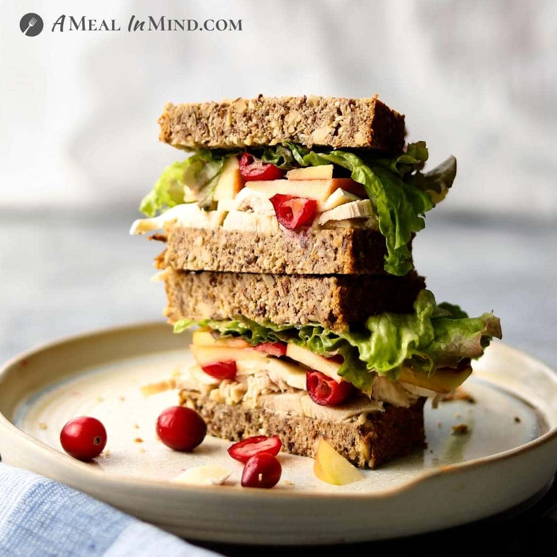 chicken-apple-brie sandwich with cranberries on ivory plate