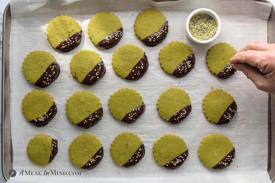 matcha cookies on tray after dipping and when applying sprinkles