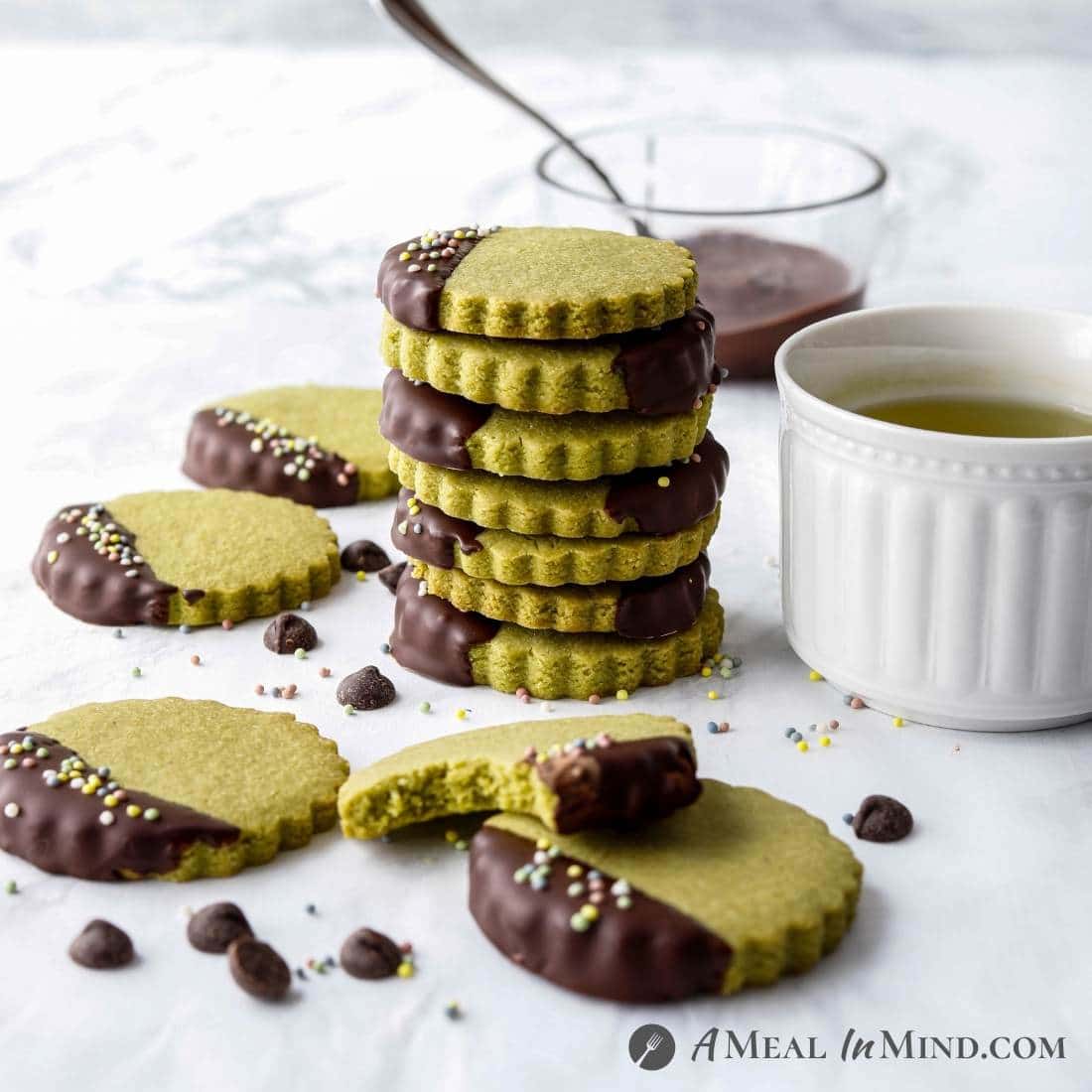 stack of dark chocolate-dipped matcha cookies with a cup of tea